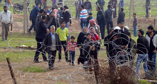 Syrians cross the border from the Syrian town of Ras al-Ain to the Turkish border town of Ceylanpinar after an air strike