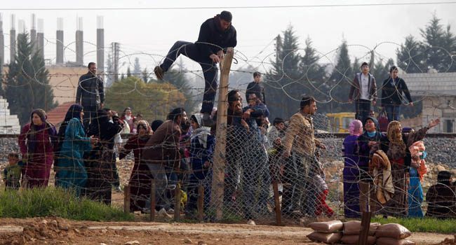 Syrians try to cross the border from the Syrian town of Ras al-Ain to the Turkish border town of Ceylanpinar after an air strike