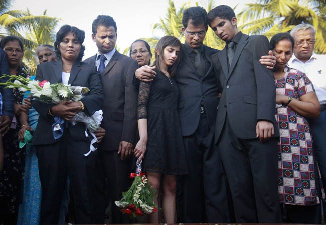 Jacintha Saldanha's widower Barboza and her children Lisha and Junal stand next to her coffin during her funeral at a cemetery in Shirva