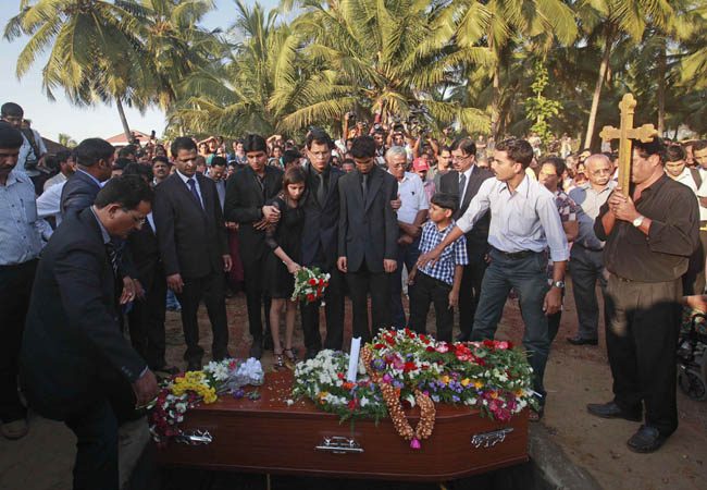 Jacintha Saldanha's widower Barboza and her children Lisha and Junal stand next to her coffin as they attend her funeral at a cemetery in Shirva