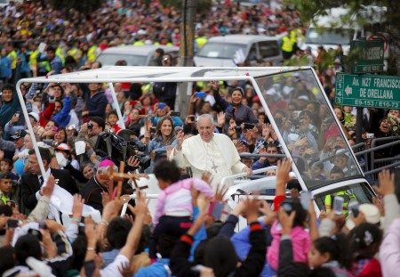Pope Francis greets the crowd of faithful from a popemobile in Quito