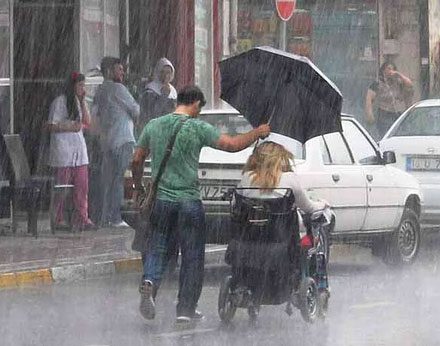 Yağmurda kendisi ıslanma pahasına engelli kadınla şemsiyesini paylaşan Bursalı genç.