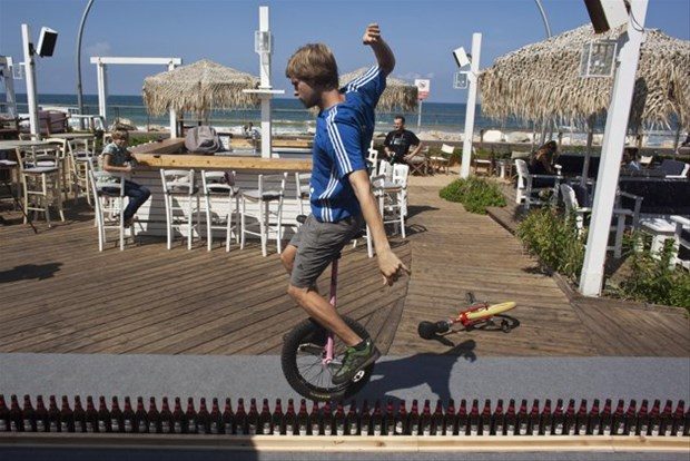 Alman Lutz Eichholz tek tekerlekli bisikletiyle 8.93 metre uzunluğunda 127 bira şişesinin üzerinden geçiyor