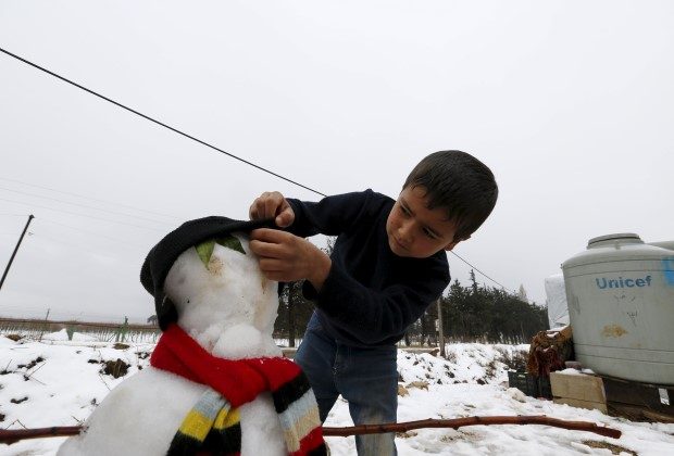 A Syrian child Mohammed from Raqqa makes a snowman in the Bekaa Valley in Lebanon after the first heavy snow storm hits Lebanon