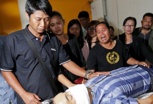 Relatives cry near the body of Thai victim Suwan Sudmun after Monday's bomb blast, at the Institute of Forensic Medicine in Bangkok