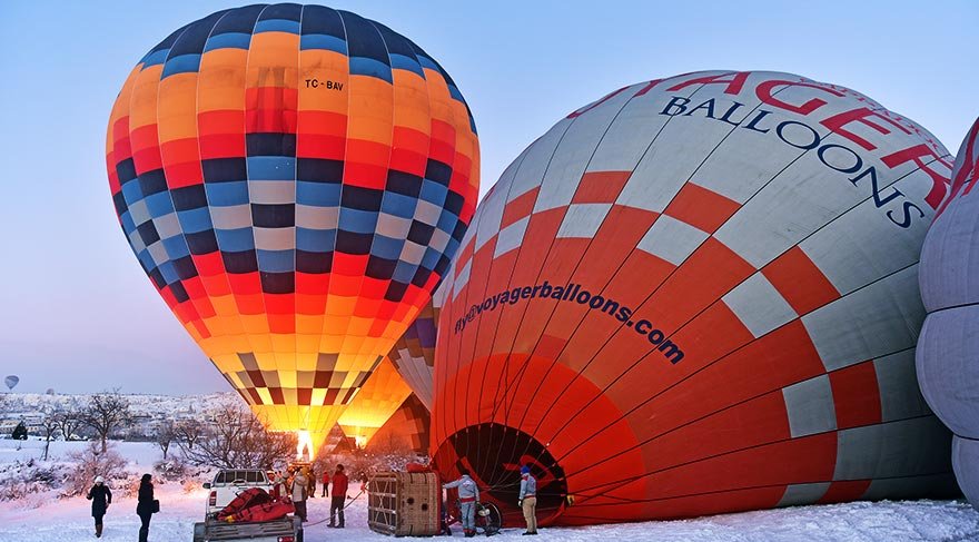 Turistler, peribacalarının beyaza bürünmüş halini görmek için soğuk havaya rağmen sabahın ilk ışıklarında balon turlarına katılıyor.